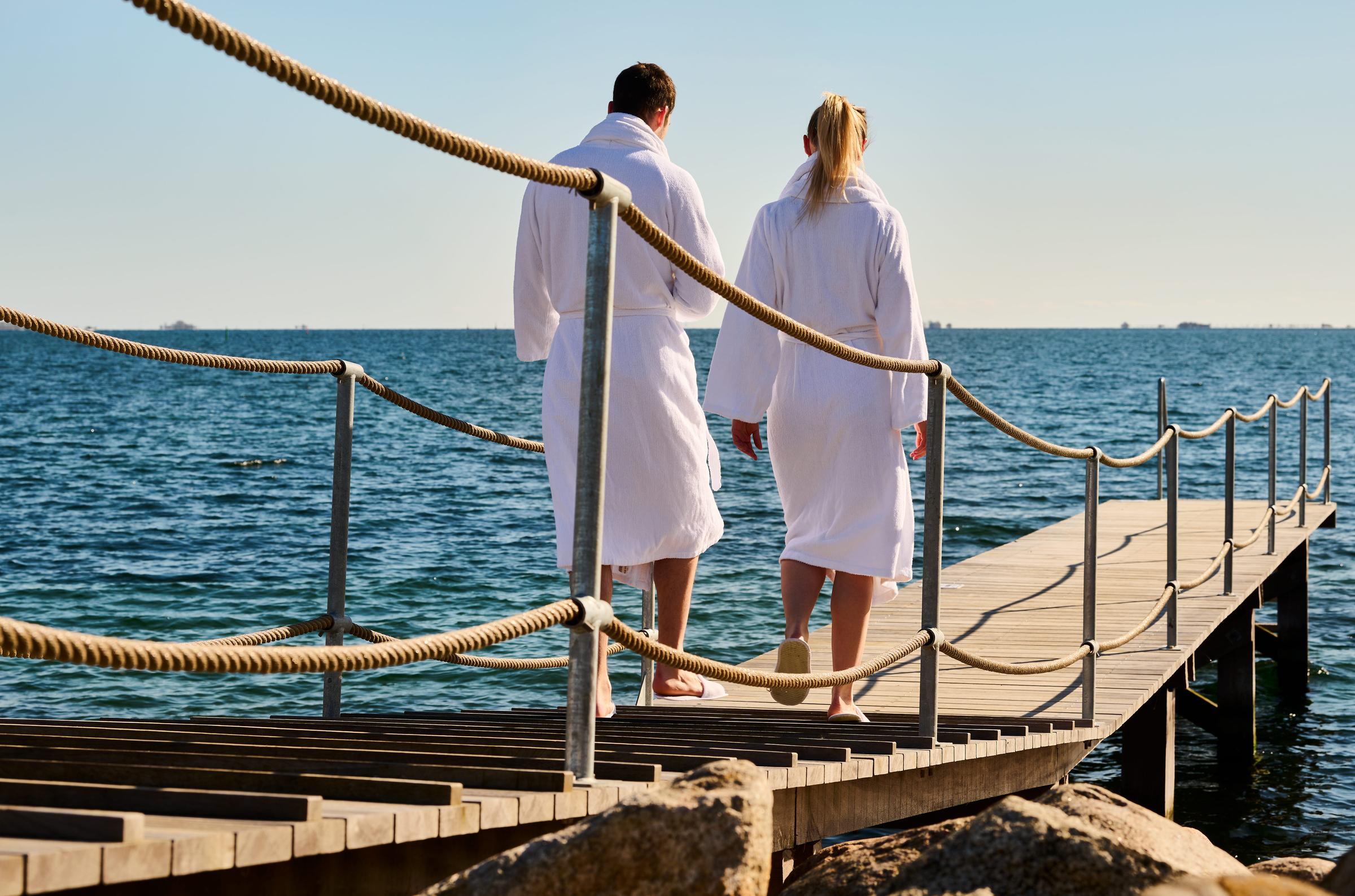 Two person in bathrobes on a pier