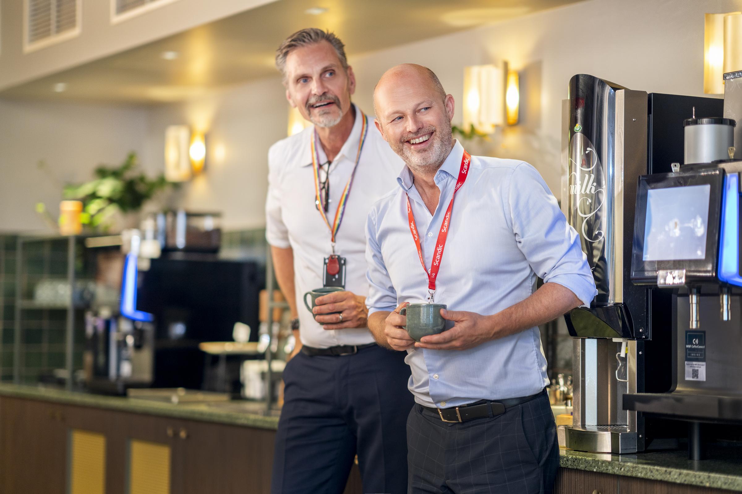 Two team members with coffee cups
