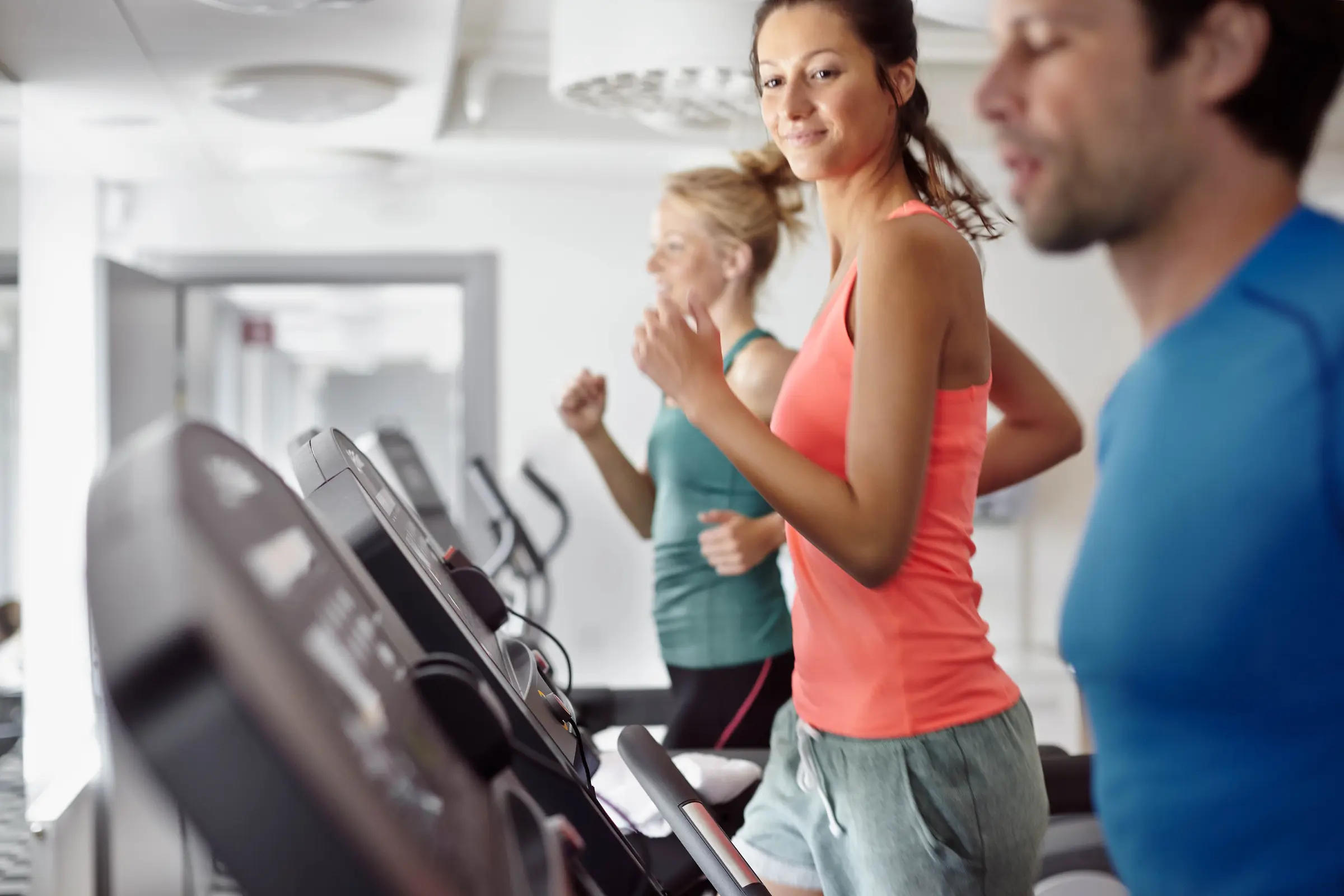 Tre personer springer på löpbandet i ett av våra gym
