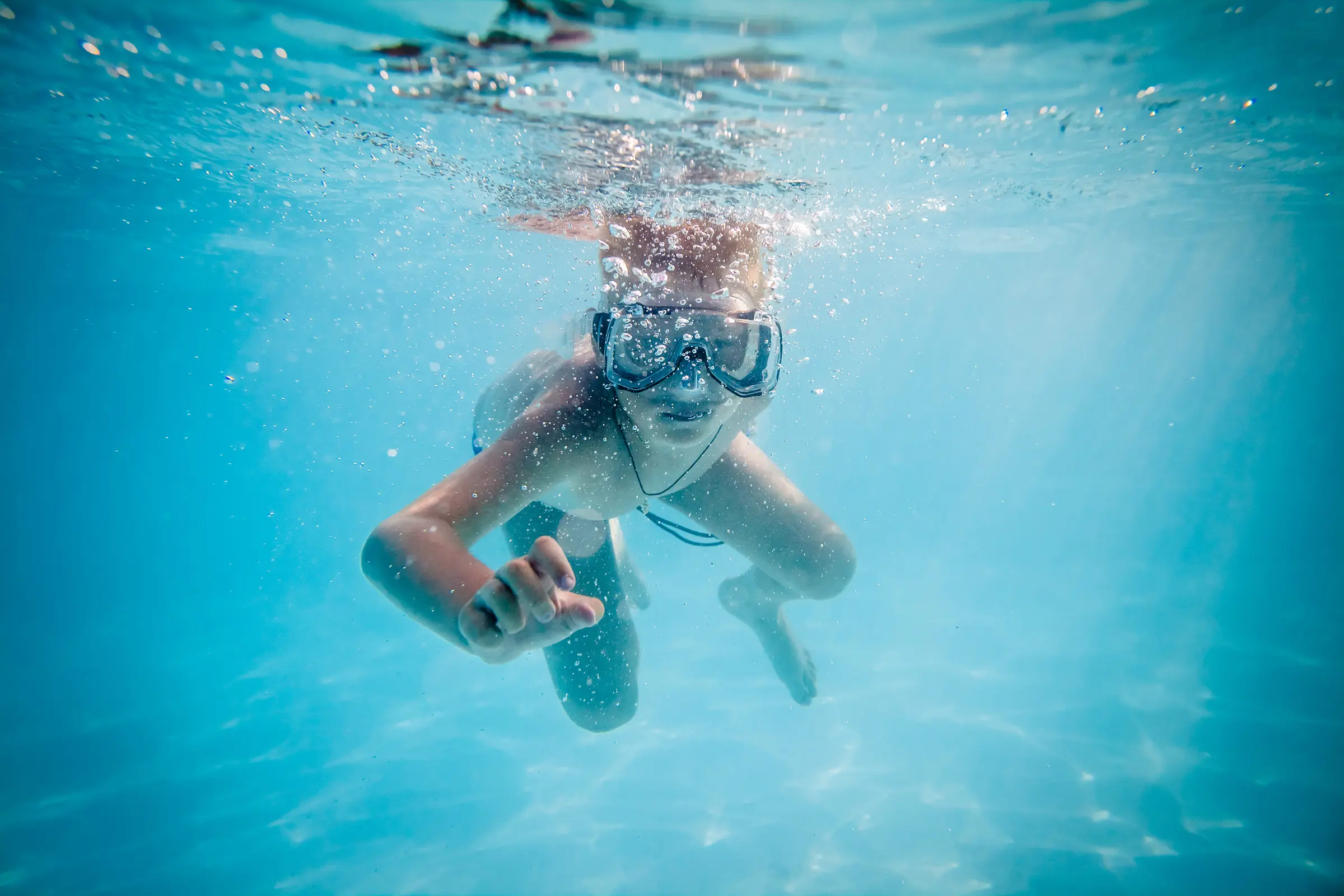 Boy swimming under water in pool